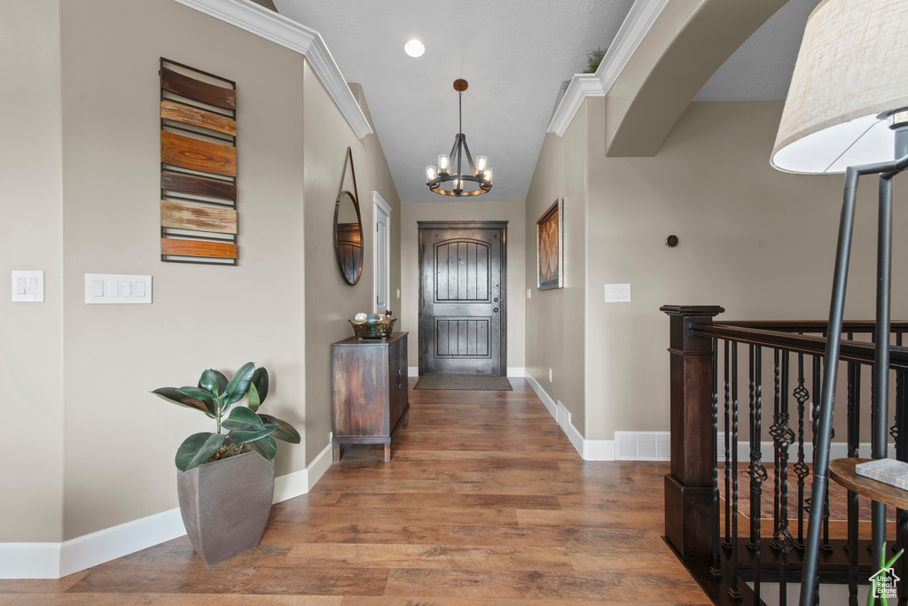 Corridor with a chandelier, wood finished floors, and baseboards