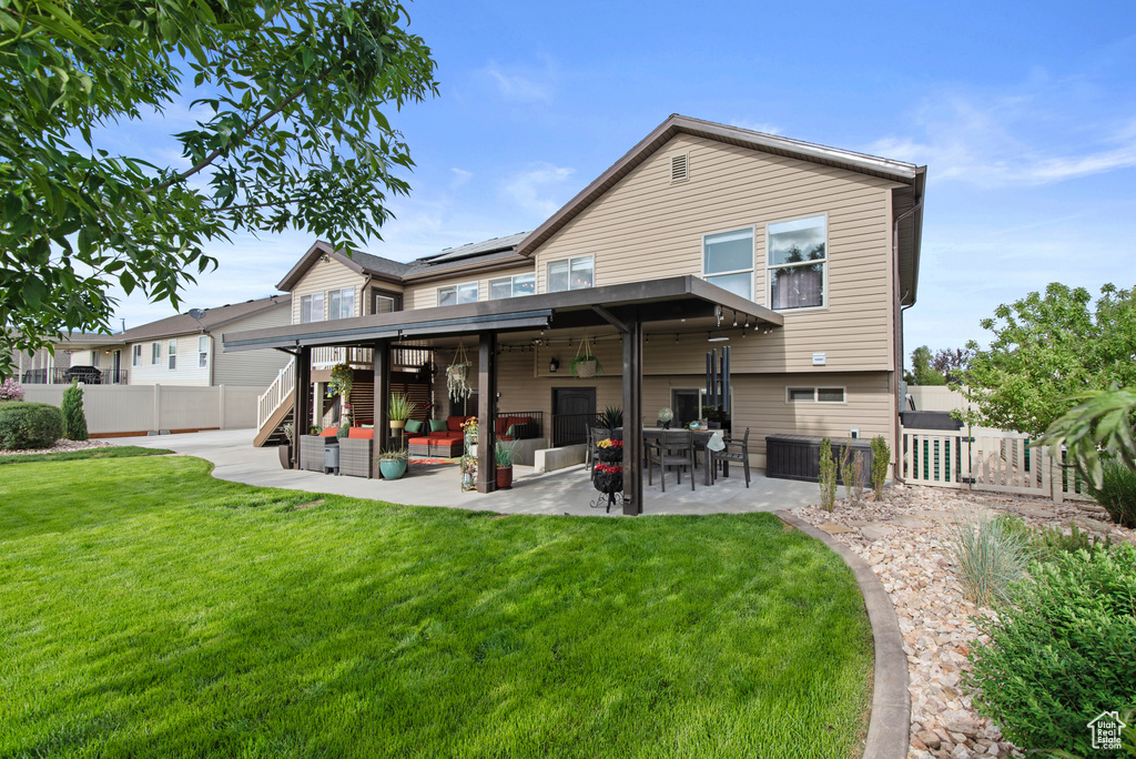 Rear view of property featuring a patio area, a gate, and roof mounted solar panels