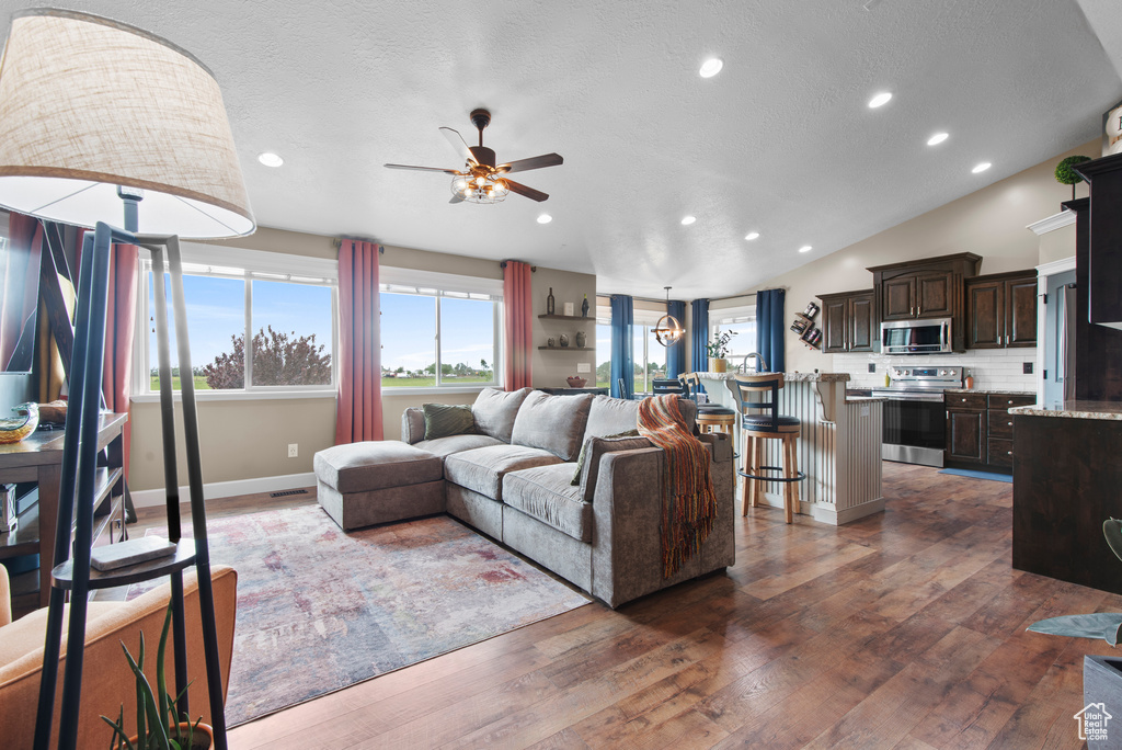 Living room with ceiling fan, recessed lighting, plenty of natural light, dark wood-type flooring, and baseboards