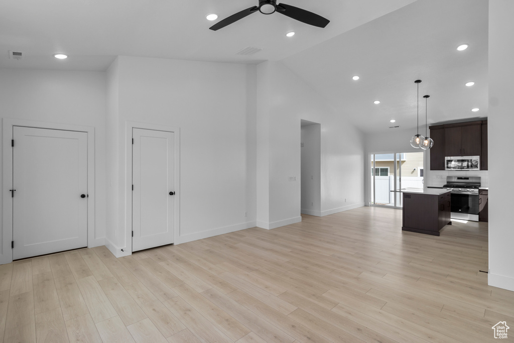 Unfurnished living room featuring ceiling fan, high vaulted ceiling, light wood-type flooring, baseboards, and recessed lighting