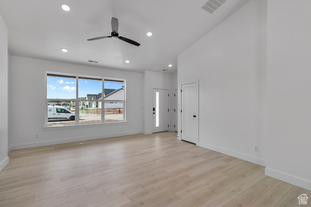 Unfurnished living room with ceiling fan, light wood-style flooring, baseboards, recessed lighting, and lofted ceiling