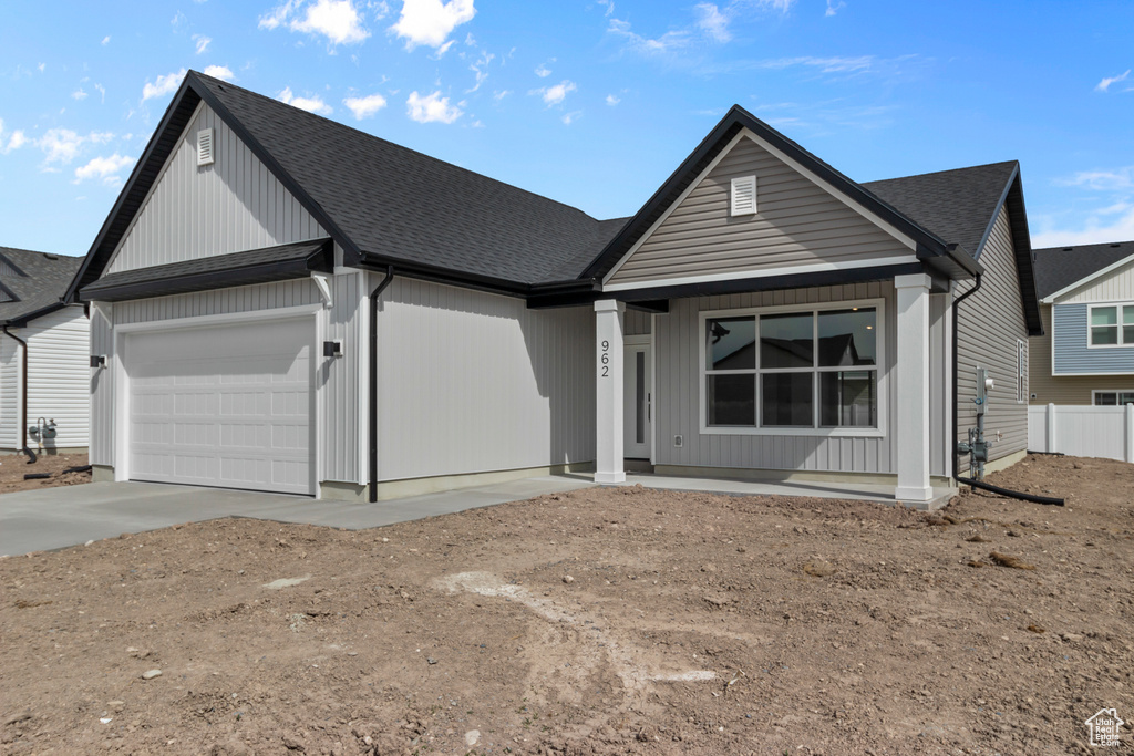 View of front of house featuring a garage, concrete driveway, a shingled roof, covered porch, and fence