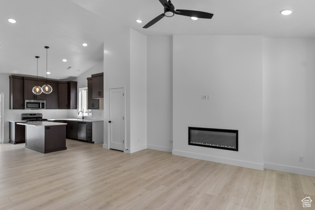 Unfurnished living room featuring a ceiling fan, a sink, a glass covered fireplace, light wood-style flooring, and recessed lighting