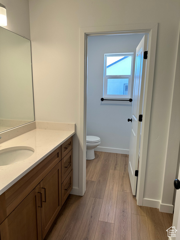 Bathroom with wood finished floors, toilet, vanity, and baseboards