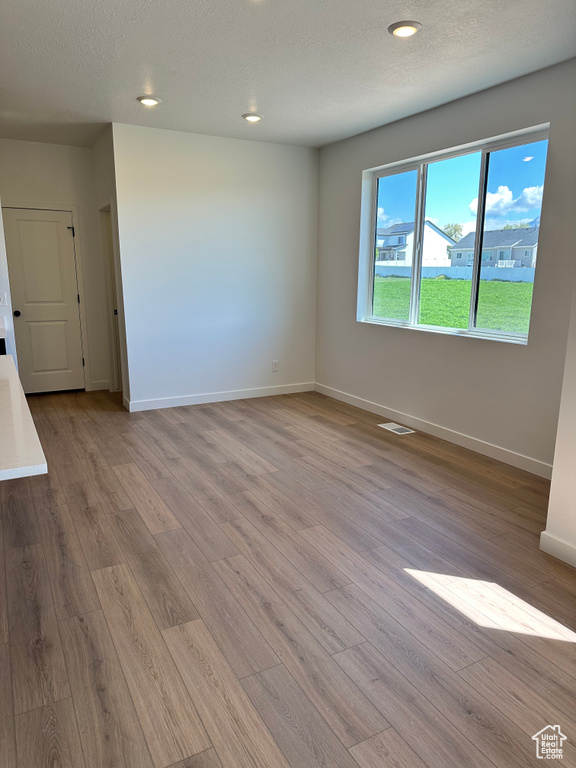 Spare room with light wood-type flooring, baseboards, recessed lighting, and a textured ceiling