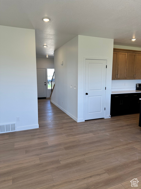 Empty room with baseboards, light wood finished floors, recessed lighting, and a textured ceiling