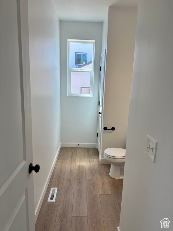 Bathroom with wood finished floors, toilet, and baseboards