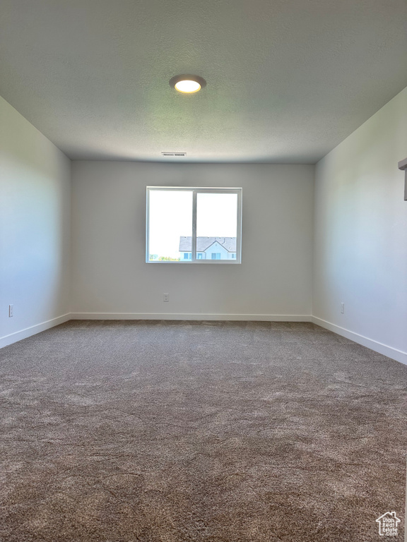 Carpeted empty room with baseboards and a textured ceiling