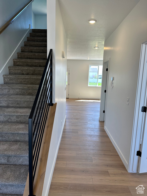 Stairway with wood finished floors, baseboards, and recessed lighting