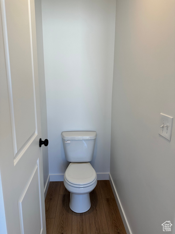 Bathroom featuring wood finished floors, baseboards, and toilet
