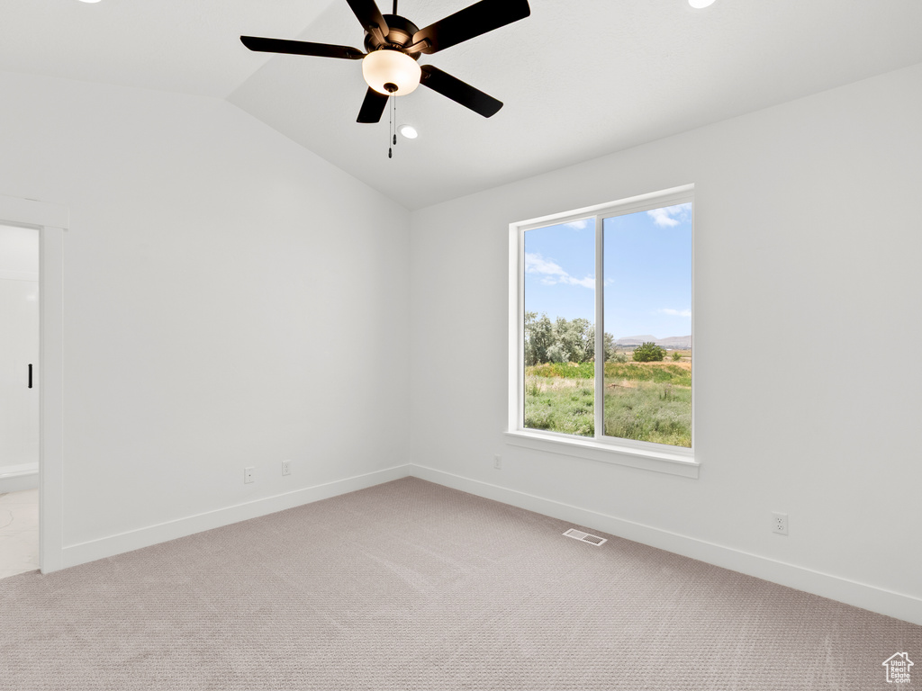 Unfurnished room featuring lofted ceiling, light colored carpet, and a ceiling fan
