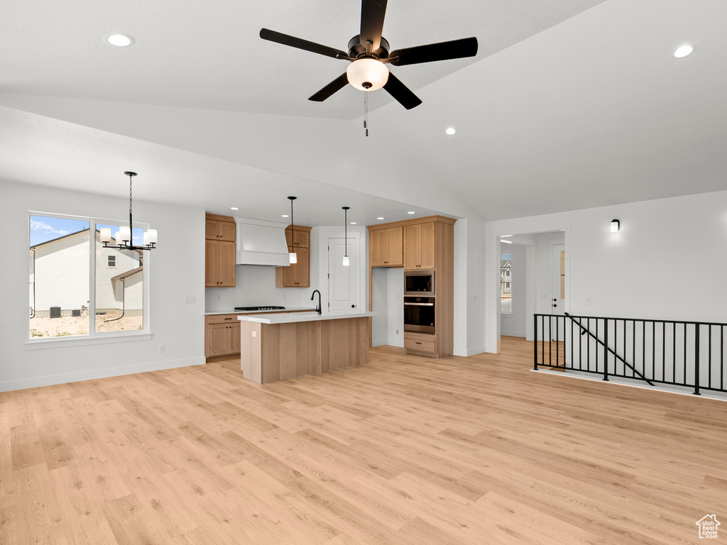 Kitchen with open floor plan, stainless steel appliances, a chandelier, light wood-style floors, and vaulted ceiling