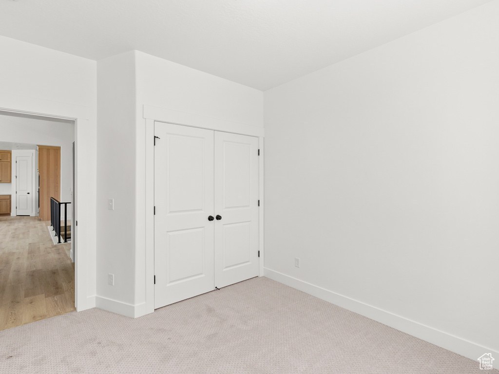 Unfurnished bedroom featuring light carpet and a closet