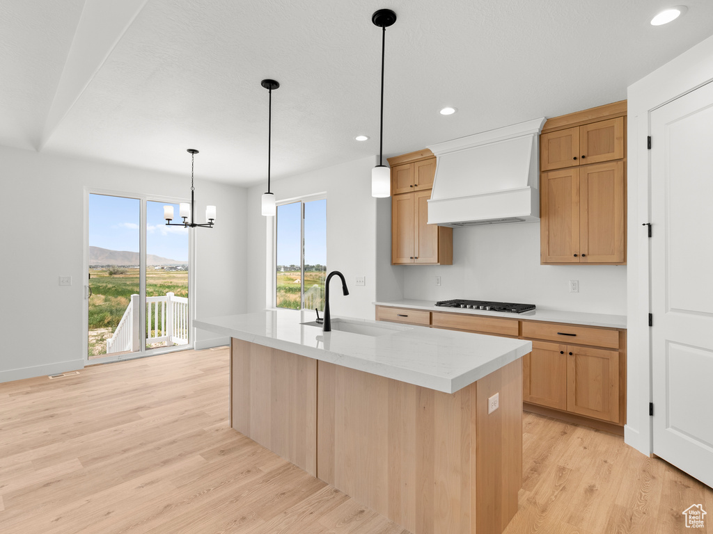 Kitchen with custom range hood, gas cooktop, healthy amount of natural light, light wood-style flooring, and recessed lighting