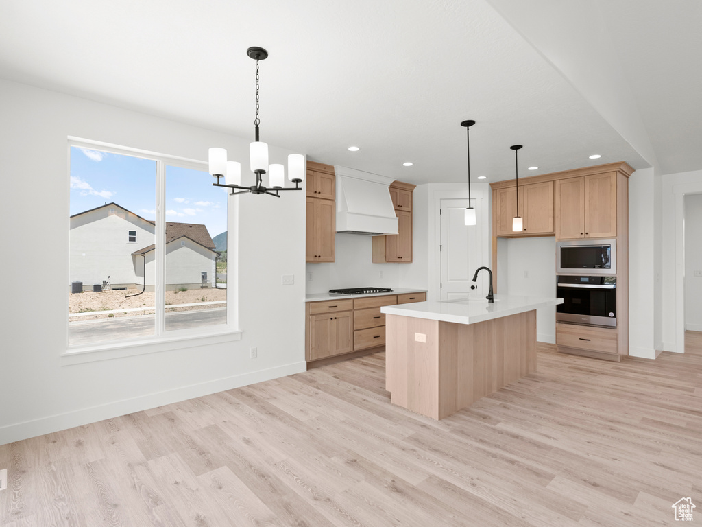 Kitchen with stainless steel appliances, custom range hood, light wood-style floors, light countertops, and recessed lighting