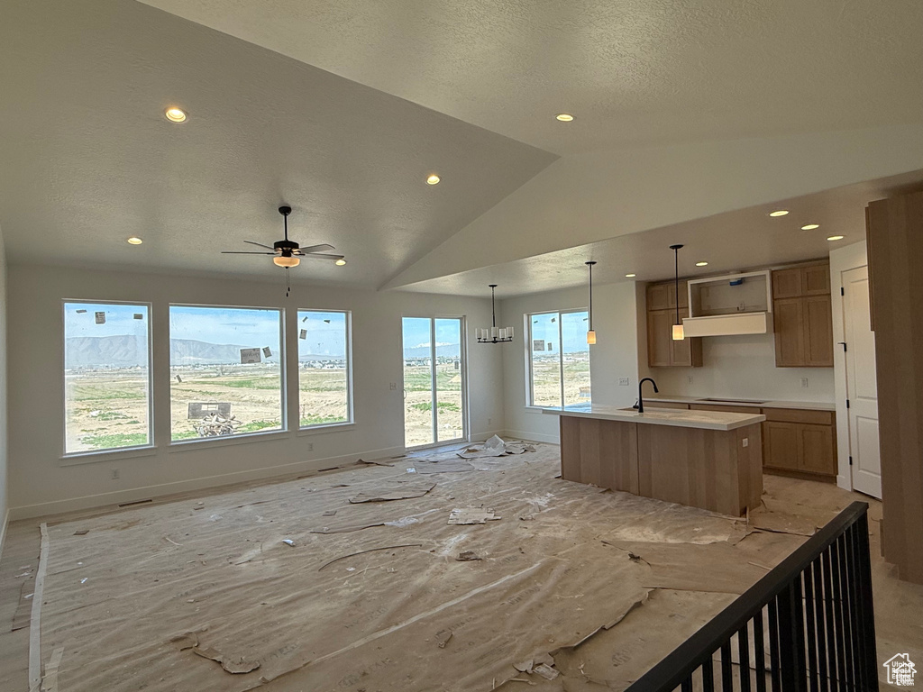 Kitchen featuring open floor plan, baseboards, an island with sink, recessed lighting, and lofted ceiling
