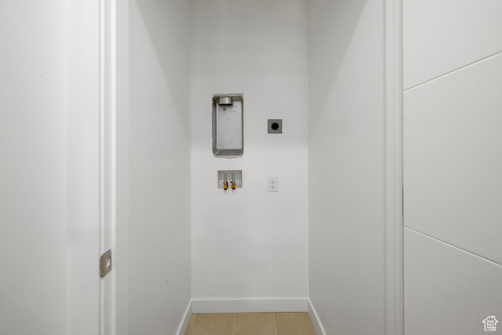Clothes washing area featuring electric dryer hookup, hookup for a washing machine, light tile patterned floors, and baseboards