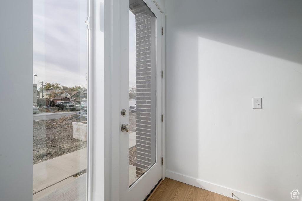 Doorway with light wood-type flooring and baseboards