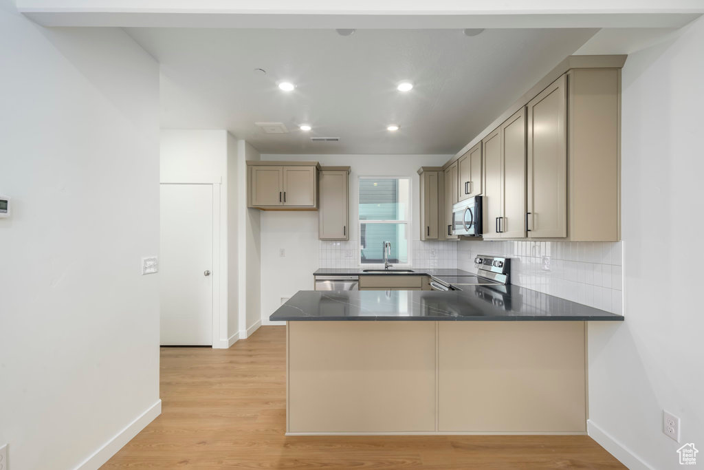 Kitchen featuring stainless steel appliances, a peninsula, tasteful backsplash, dark countertops, and baseboards
