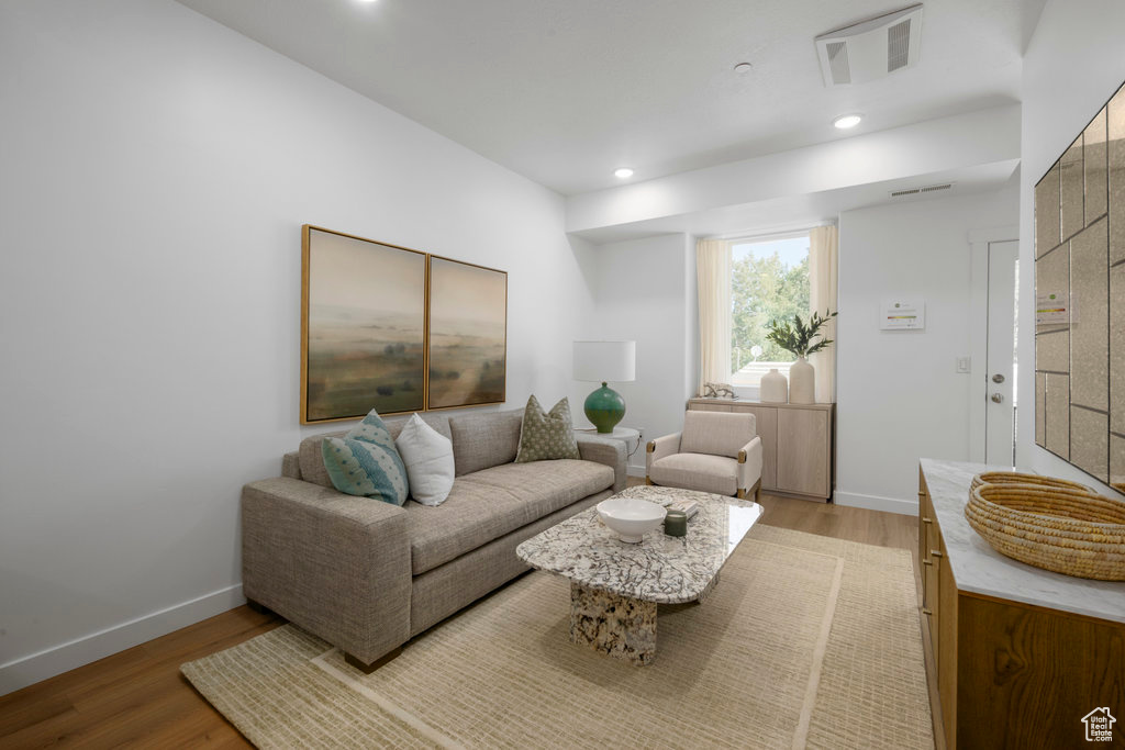 Living room with light wood finished floors, baseboards, and recessed lighting