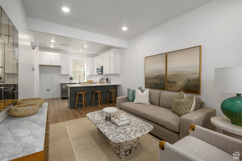 Living area with light wood-type flooring and recessed lighting