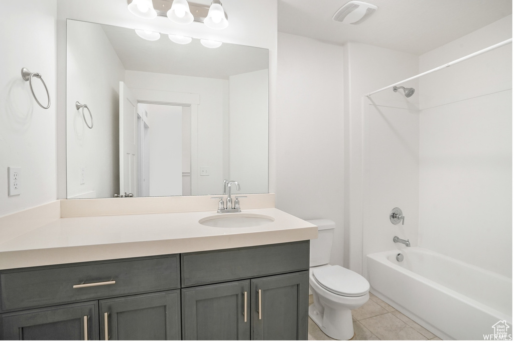 Full bathroom with toilet, tile patterned floors, vanity, and shower / bathtub combination