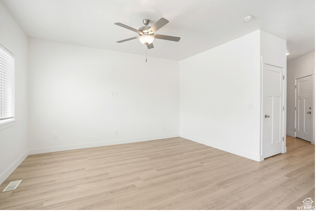 Unfurnished room featuring a ceiling fan, light wood-style floors, baseboards, and a smoke detector
