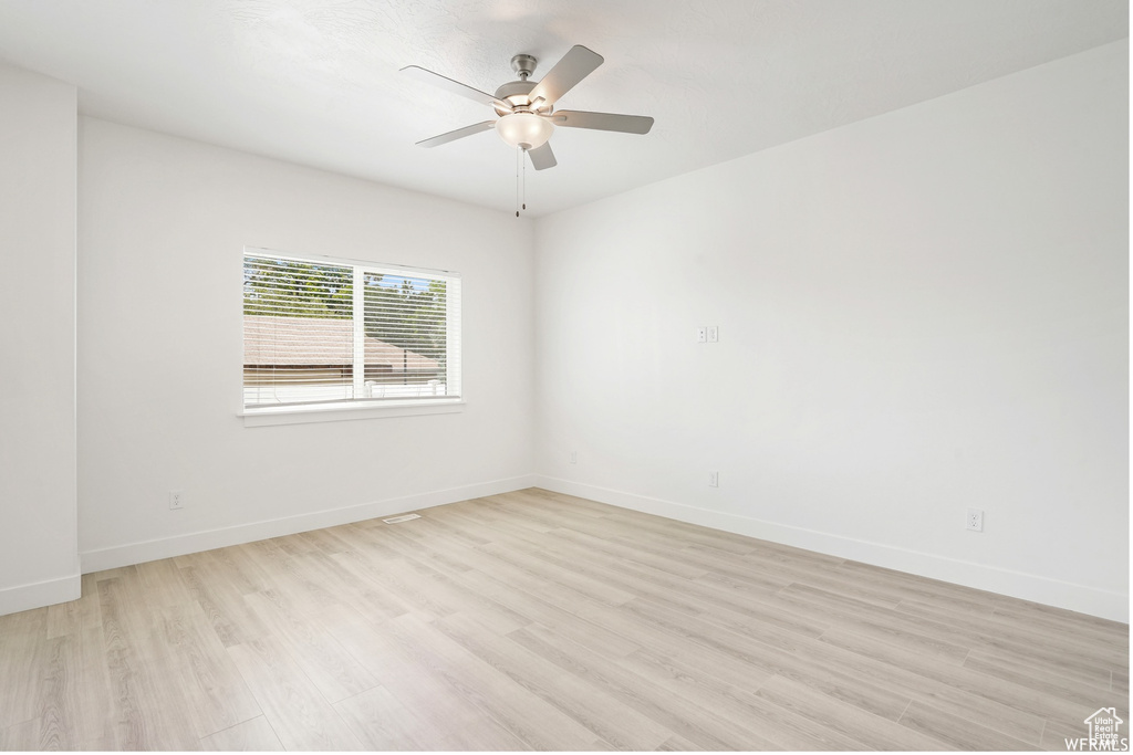 Spare room featuring light wood-style flooring, baseboards, and a ceiling fan