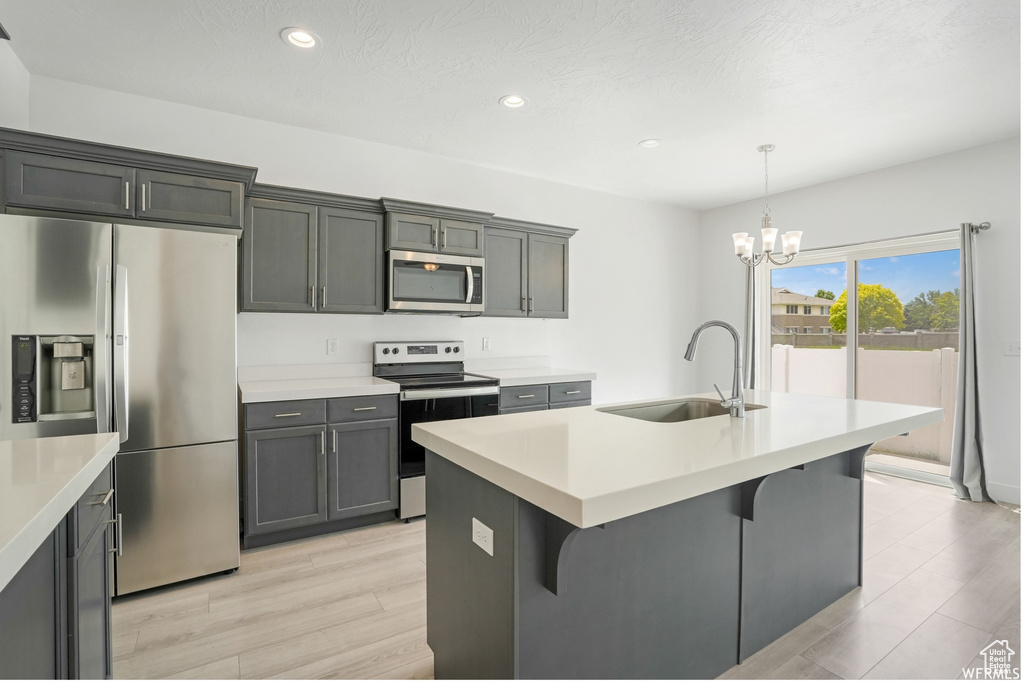 Kitchen with stainless steel appliances, a sink, a chandelier, light wood finished floors, and recessed lighting