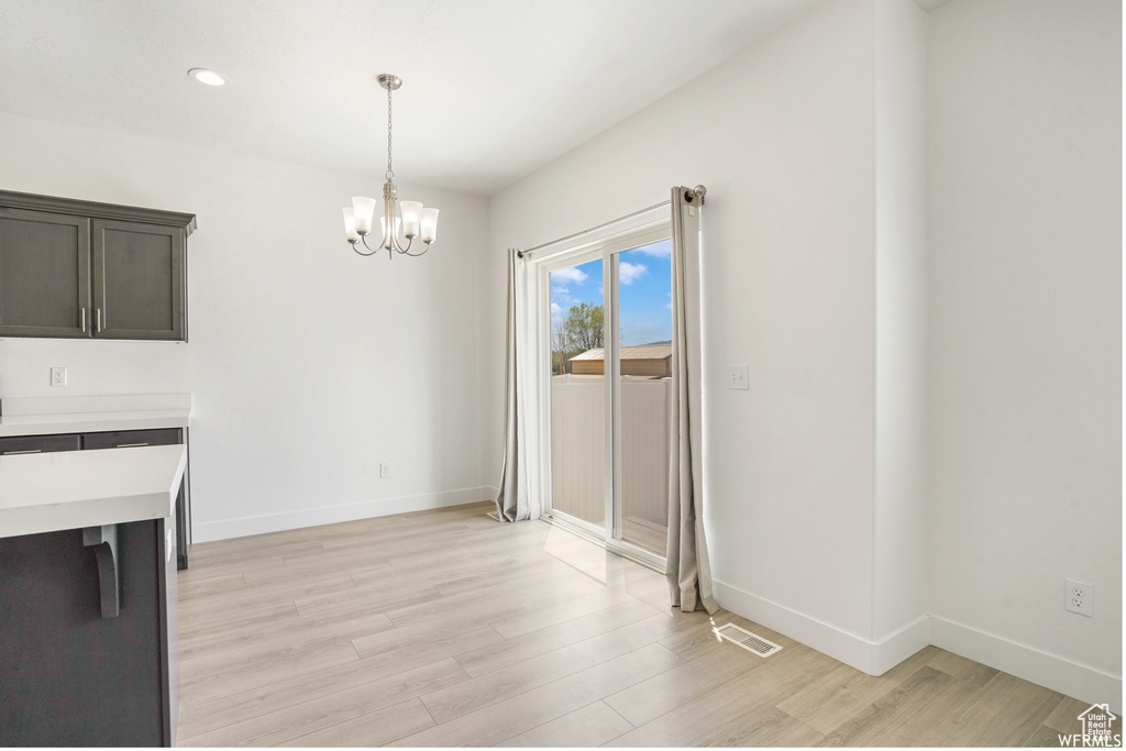 Unfurnished dining area with light wood-style floors, a chandelier, baseboards, and recessed lighting