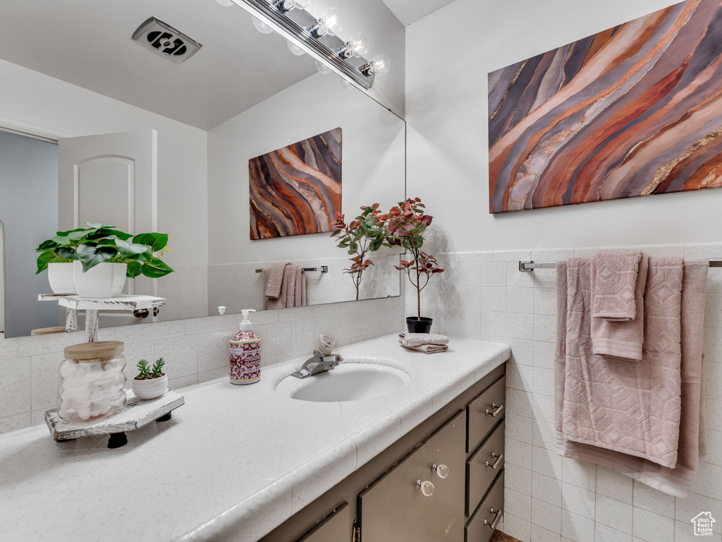 Bathroom with tile walls, vanity, and wainscoting