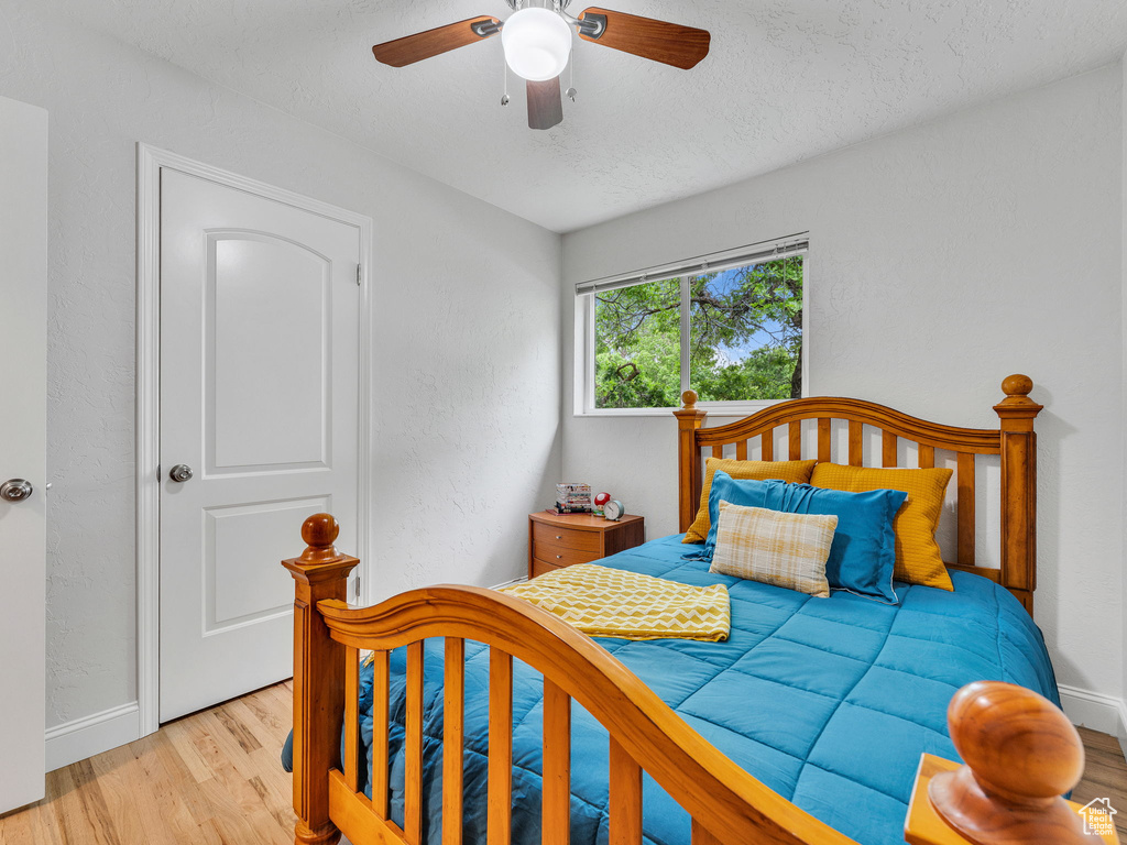 Bedroom with light wood-type flooring, baseboards, a textured ceiling, and ceiling fan