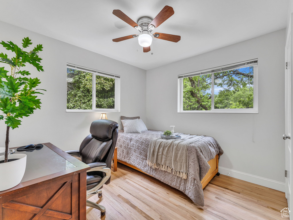 Bedroom featuring baseboards, light wood-style floors, a desk, and a ceiling fan