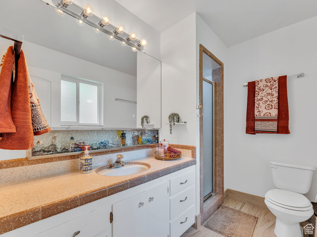 Bathroom with toilet, a shower stall, vanity, and baseboards