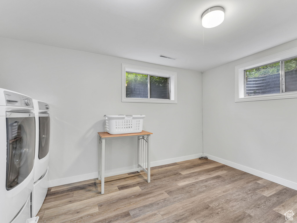 Laundry room featuring washing machine and dryer, light wood-style floors, and baseboards