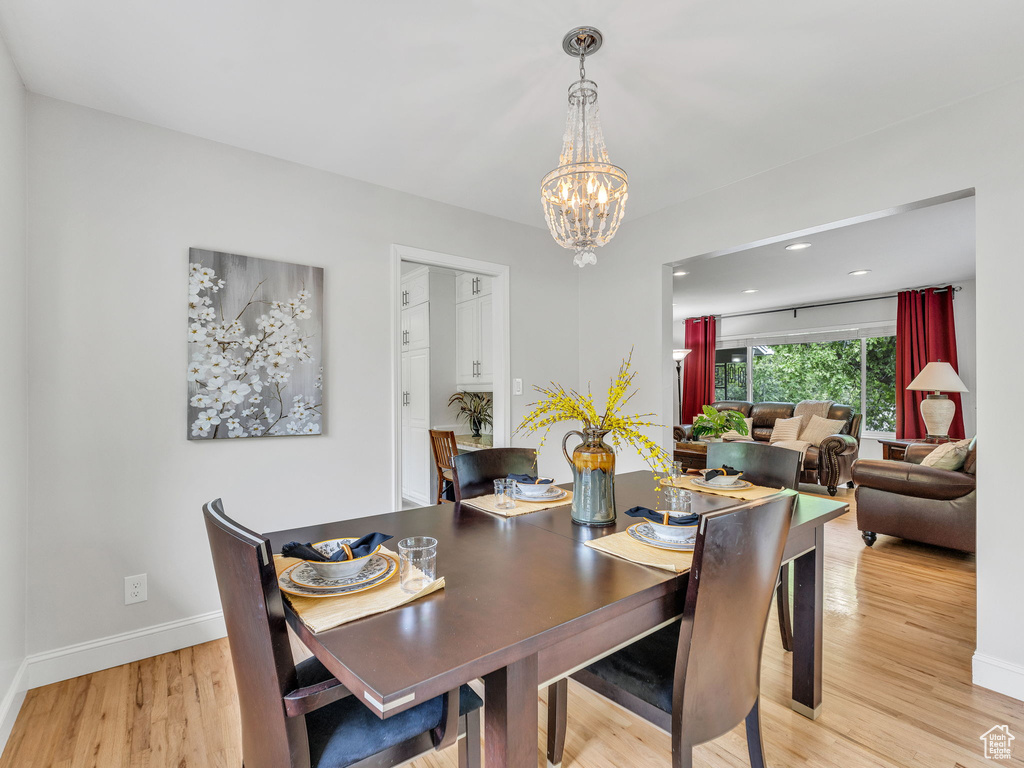 Dining area featuring a chandelier, light wood-style flooring, baseboards, and recessed lighting