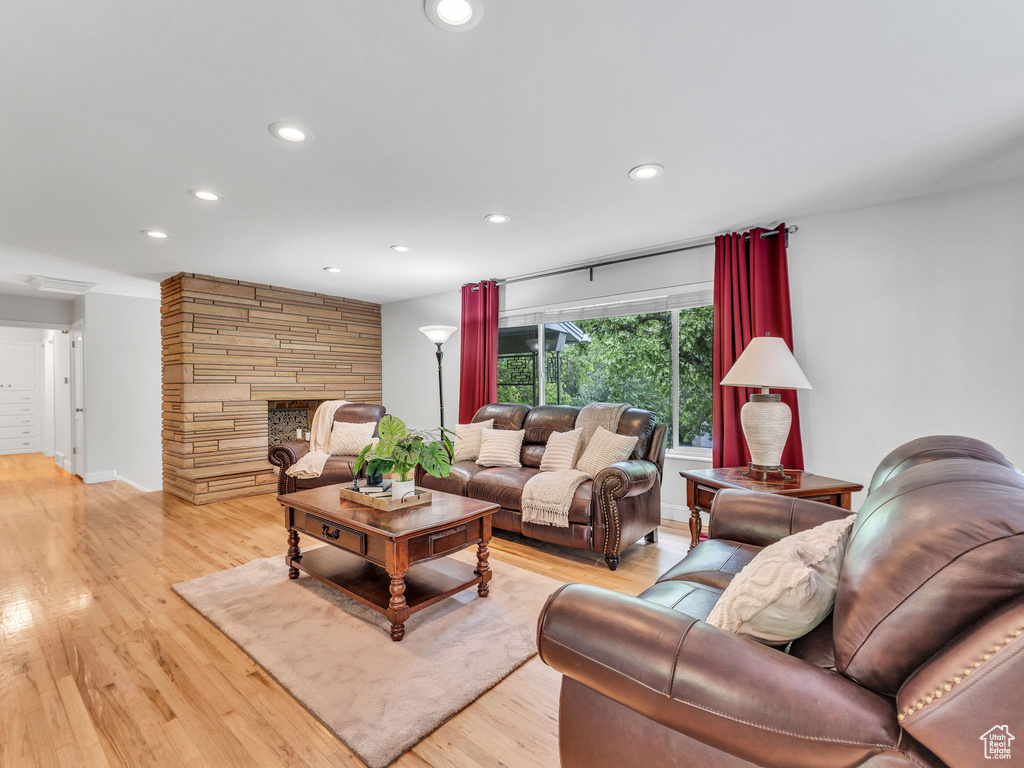 Living room featuring recessed lighting, light wood-type flooring, and a fireplace