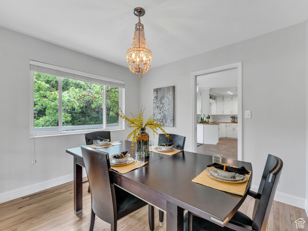 Dining area with a chandelier, baseboards, and light wood-style flooring
