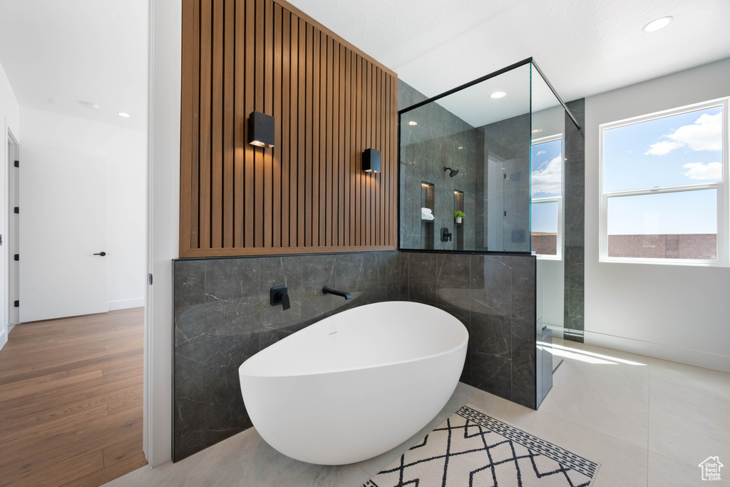 Full bathroom with walk in shower, a freestanding bath, tile walls, and recessed lighting