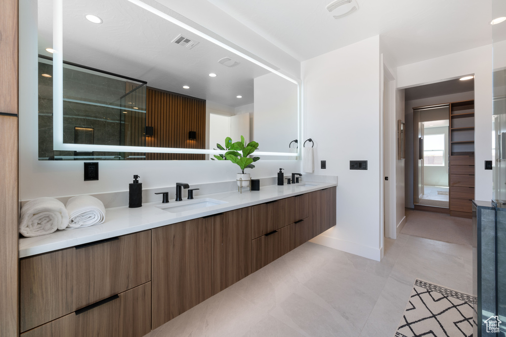Bathroom with double vanity, baseboards, recessed lighting, and a shower with shower door