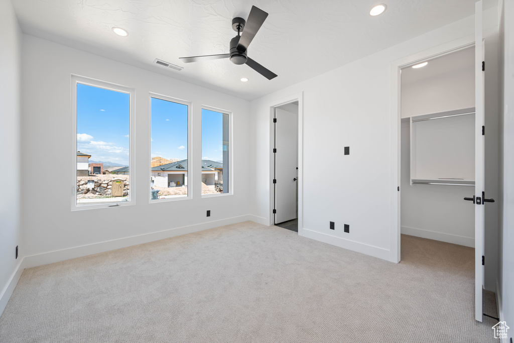 Unfurnished bedroom with carpet, a spacious closet, recessed lighting, baseboards, and a ceiling fan