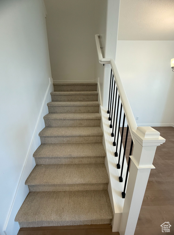 Staircase with wood finished floors and baseboards