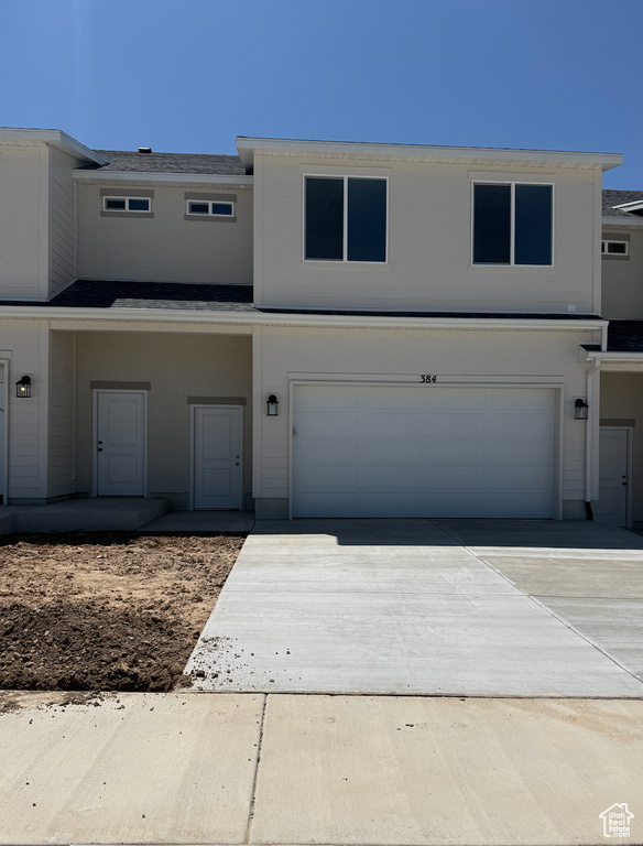 Townhome / multi-family property featuring an attached garage, concrete driveway, and roof with shingles