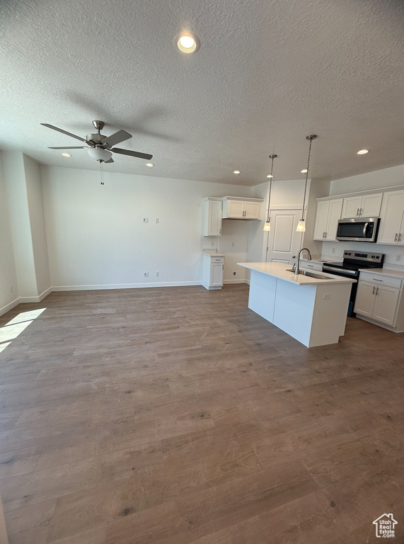 Kitchen with appliances with stainless steel finishes, a textured ceiling, a sink, a kitchen island with sink, and recessed lighting