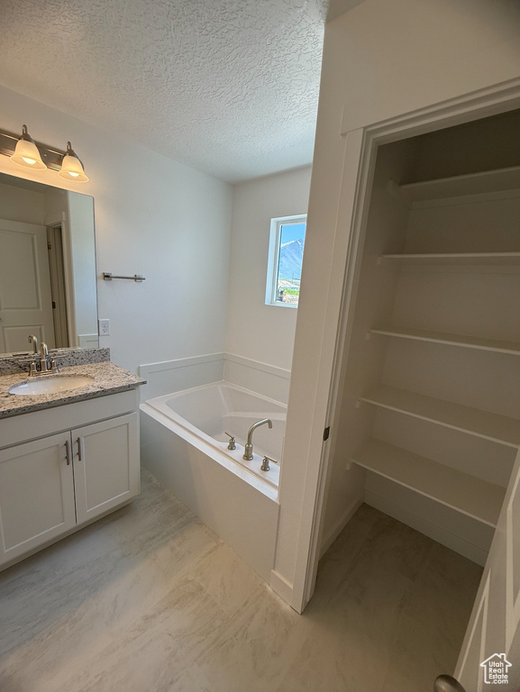 Bathroom with vanity, a textured ceiling, and a garden tub