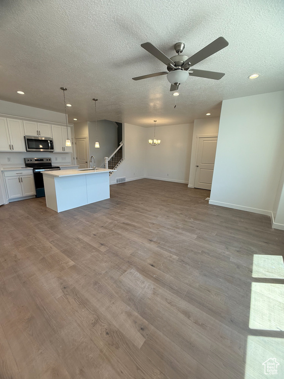 Kitchen with stainless steel appliances, a textured ceiling, a ceiling fan, open floor plan, and recessed lighting