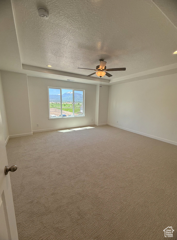 Unfurnished room with a textured ceiling, light colored carpet, ceiling fan, baseboards, and a smoke detector