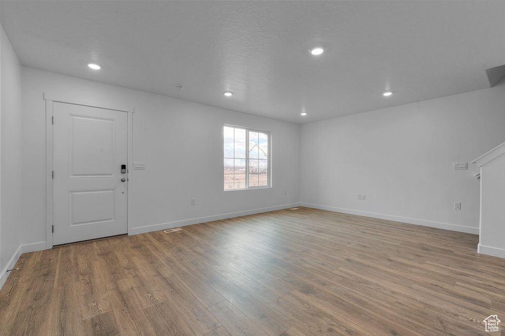 Unfurnished living room featuring wood finished floors, baseboards, and recessed lighting