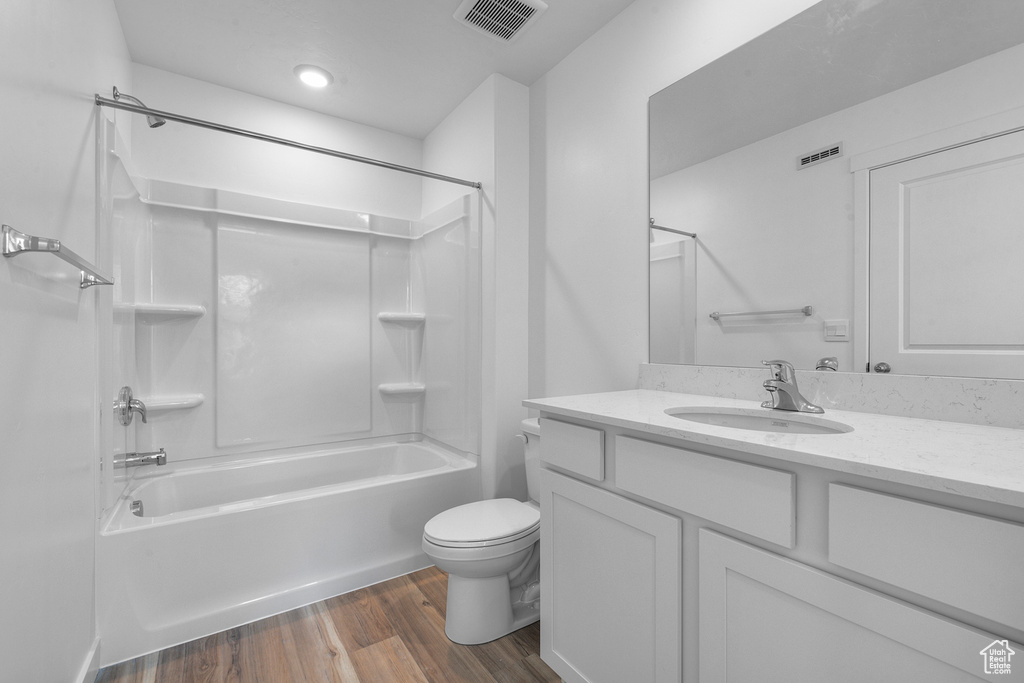 Bathroom with wood finished floors, toilet, shower / washtub combination, and vanity