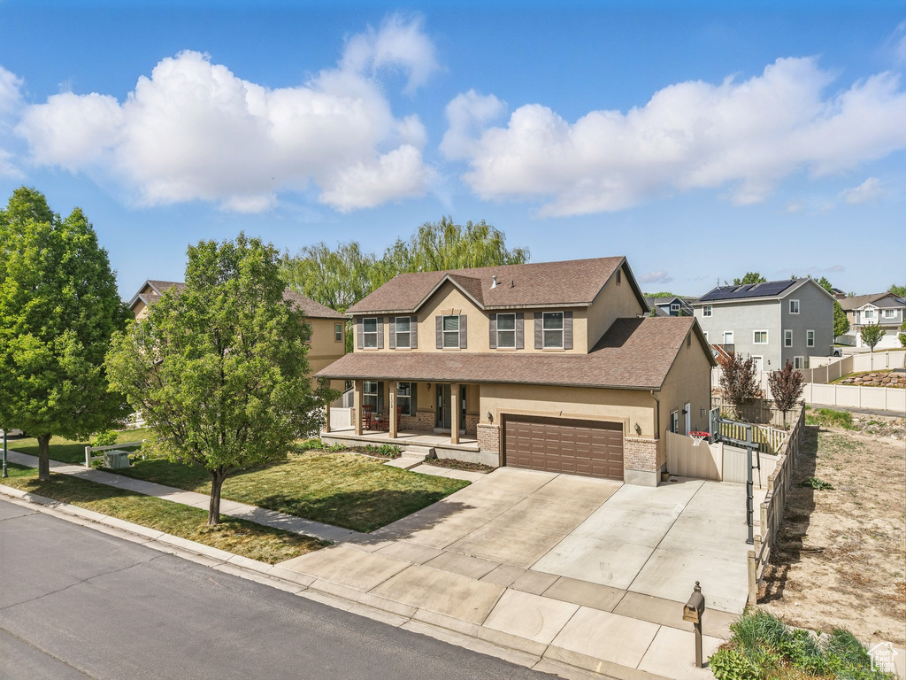 View of front of house with fence, covered porch, stucco siding, driveway, and a residential view